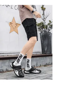 Detailed view of stylish black and white mens breathable beach clogs worn by model