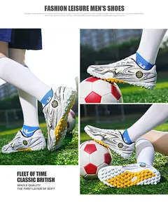 Detailed view of white and gold patterned soccer shoes on a green grass field