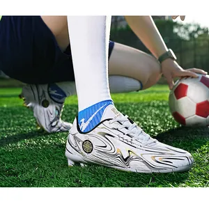 Action detail shot of white soccer cleats with gold swirls on green turf field