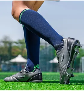 Detailed close-up of professional grey soccer cleats with studs on a green field.