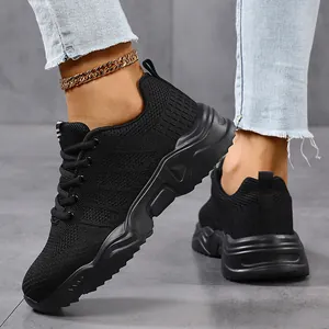 Close-up side view of breathable black fly-knit unisex sneakers worn with a gold anklet