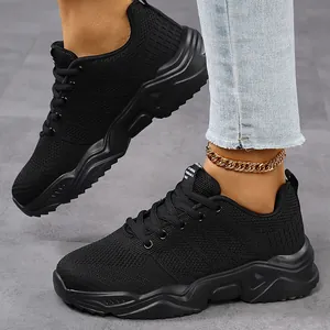 Close-up view of black breathable mesh sneakers on feet with a stylish gold anklet detail