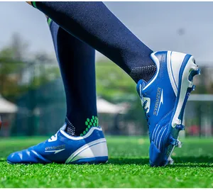 Close-up of blue and white breathable spiked soccer cleats on a green turf field