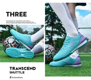 Detail shot of turquoise TF soccer cleats on green grass with football background.