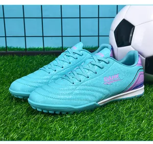 Detailed close-up showing texture of cyan TF soccer shoes on green artificial turf field