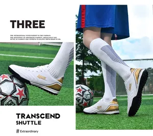 White soccer shoes with gold accents and TF studs shown in action on a grass field.