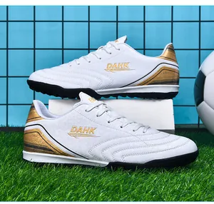 White soccer shoes with gold accents and TF turf studs on artificial grass background