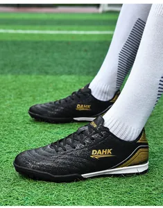 Detailed side view of black soccer shoes with gold accents on professional turf