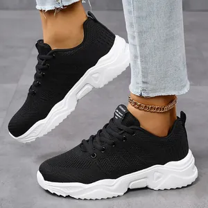Close-up of black breathable flyknit sports sneakers with white thick soles.