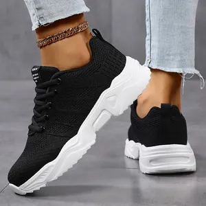 Detail view of breathable black fly-knit sneakers with chunky white sole and laces.