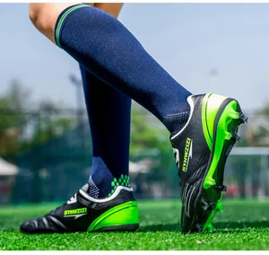 Detailed side view of breathable black and green soccer cleats on artificial turf