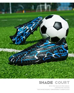 Low-top soccer shoes with blue flame pattern on a professional green grass field