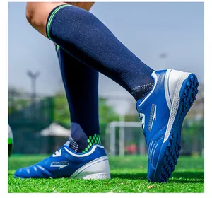 Detailed shot of blue and white soccer cleats with breathable mesh on green turf