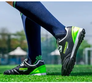 Detailed view of black and neon green soccer cleats worn on a grass field