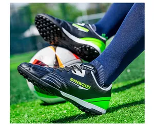 Close-up detail of breathable black and neon green soccer cleats on grass field