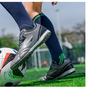 Action shot showing breathable gray turf soccer shoes on a field with a soccer ball.