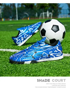 Detail of blue low-top football shoes on green grass with a soccer ball background