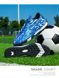 Close-up view of blue low-top soccer shoes with turf studs on artificial grass field