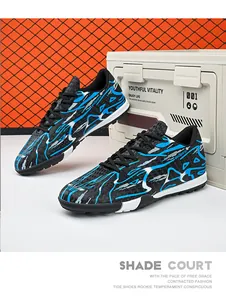 Detailed side view of black and blue patterned low-top soccer shoes for artificial grass training