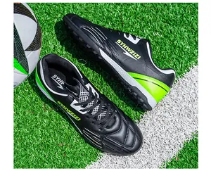 Close-up of black soccer shoes with neon green accents on an artificial turf field