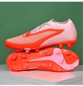 Close-up detail of pink fly-knit soccer cleats showing FG/AG studs and side pattern