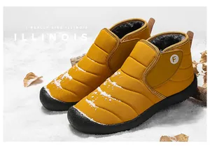 Close-up of yellow winter snow boots with fur lining on a snowy outdoor background