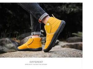 Outdoor detail view of yellow winter snow boots with warm lining worn on rocky ground