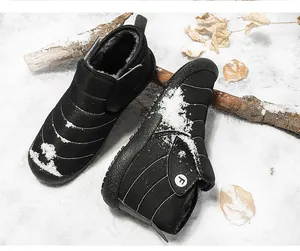 Detailed view of black winter snow boots with warm fleece lining on a snowy surface outdoors