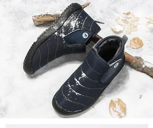 High-angle detailed shot of navy blue fleece-lined winter snow boots on a snow-covered surface