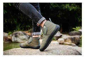 Close-up detail of olive green insulated snow boots worn on rocky outdoor terrain