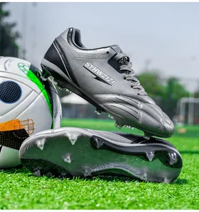 Professional silver soccer cleats with long studs displayed on a green grass field near a ball