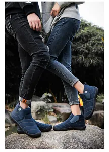 Outdoor detail of a couple wearing warm blue winter snow boots while standing on rocks