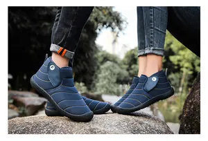 Close-up of navy blue winter snow boots with plush lining worn by a couple in outdoor setting