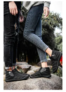 Couple wearing black outdoor snow boots with warm lining and non-slip soles on rocks.