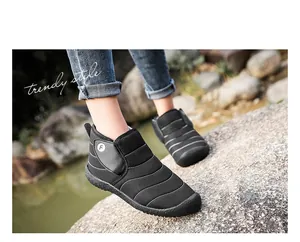 Close-up of black outdoor winter snow boots with warm lining worn on a rocky terrain