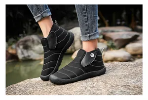 Close-up of black quilted outdoor snow boots with Velcro straps in a natural setting