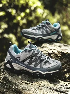 Dettaglio di scarpe da trekking traspiranti con marchio 'OUTDOOR' su una roccia.