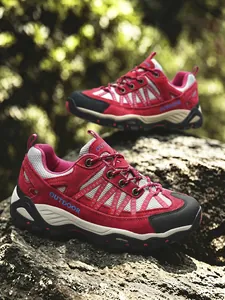 Vista dettagliata di scarpe da trekking traspiranti rosse e grigie su una roccia