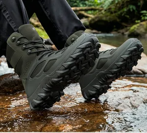 Macro shot of olive green tactical boots with thick tread sole on outdoor stream rocks.
