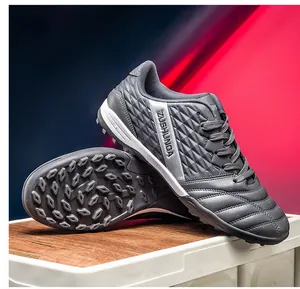 Detail view showing grey outdoor soccer shoes with turf cleats and textured upper