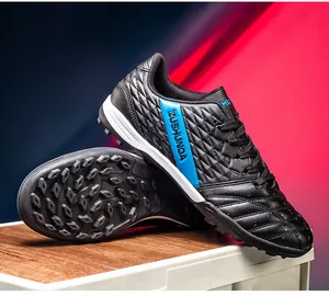 Detail of black soccer shoes with blue accents showing the side logo and turf sole