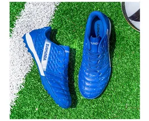Close-up view of blue turf soccer shoes with ZUSHUNDA branding on artificial grass