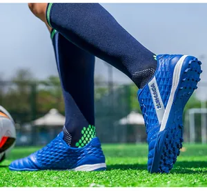 Detailed view of blue turf soccer shoes on grass showing sole and scale texture.