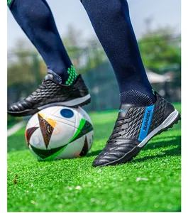 Action shot of black turf soccer shoes with ZUSHUNDA branding on a green soccer field
