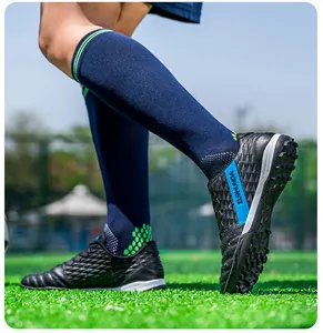 Close-up of black soccer cleats with turf studs worn on green grass during training