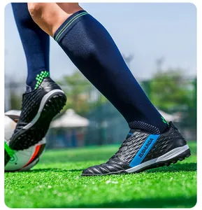 Close-up of black football shoes with blue stripe for outdoor grass training.