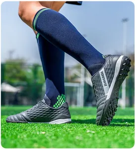 Close-up detail of low-top turf soccer shoes with textured upper on green field