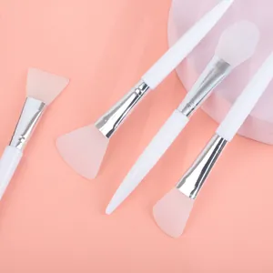 Vue rapprochée de quatre pinceaux de masque en silicone avec têtes roses et manches blancs pour soin