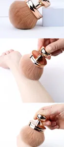 Detailed view of soft mushroom head makeup brush with rose gold handle applied to skin