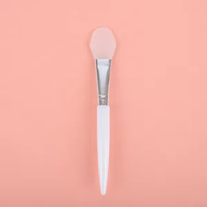 Professional soft silicone facial mask brush applicator with white handle on pink background